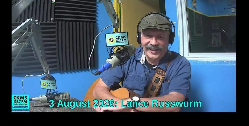 A smiling man with a moustache holding a guitar and wearing a flat cap and headphones sits at a microphone. The CKMS Community Connections icon is at the bottom to the left of "3 August 2026: Lance Russwurm"