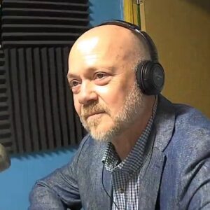 A man wearing headphones and a suit jacket.
