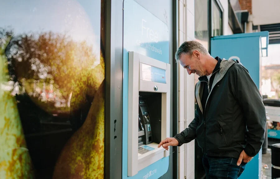 Senior man is at an ATM withdrawing some funds.