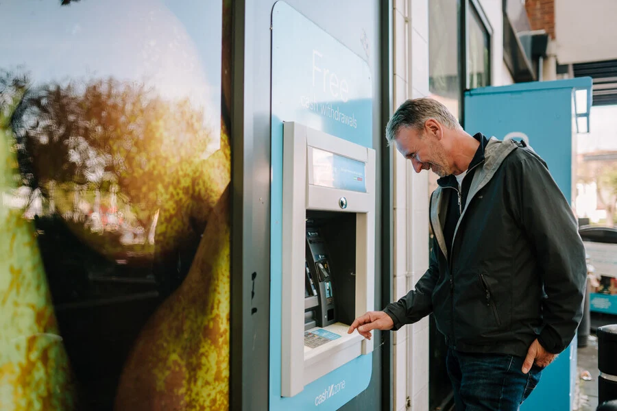 Senior man is at an ATM withdrawing some funds.